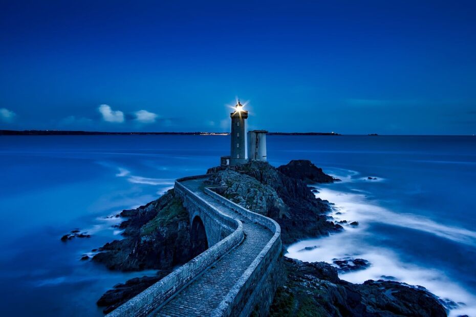 Dans l'obscurité le phare éclaire la mer de sa lumière sous un horizon bleuté