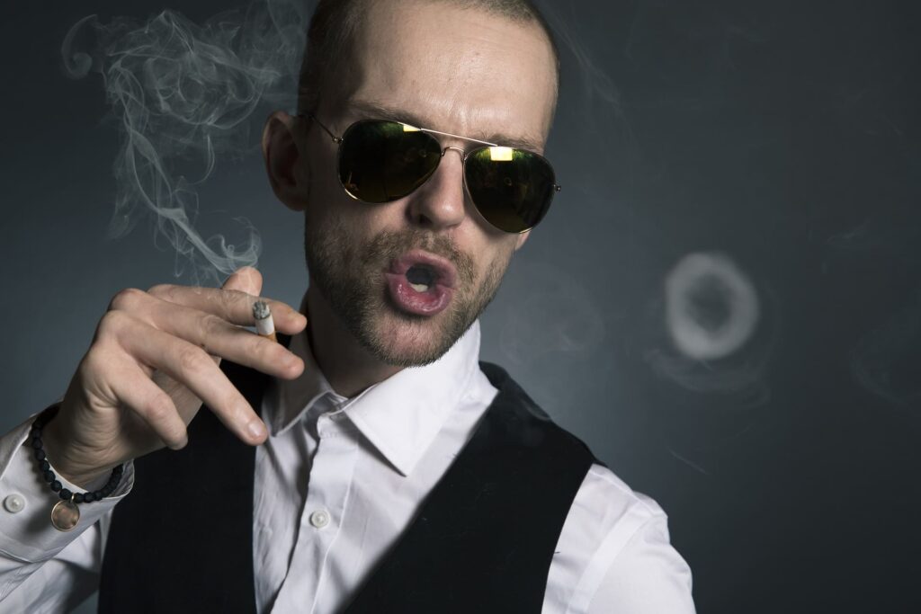 Un homme prétentieux en train de fumer avec des lunettes et qui a une surestime de soi.