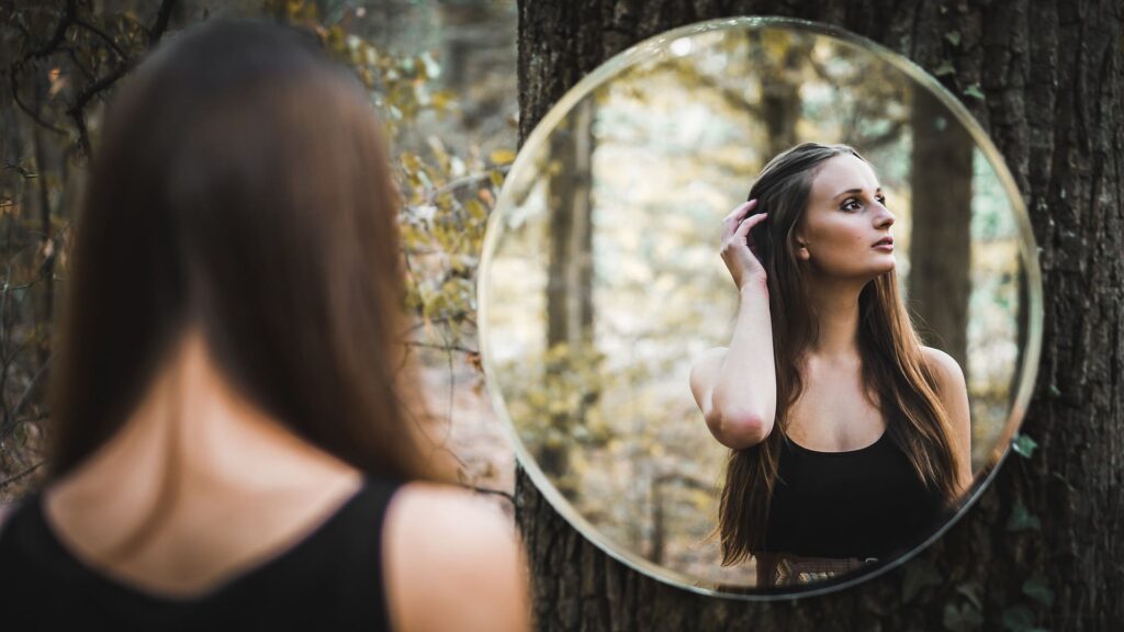 Une femme dévie le regard de son miroir par ego spirituel. C'est l'un des pièges de la spiritualité.