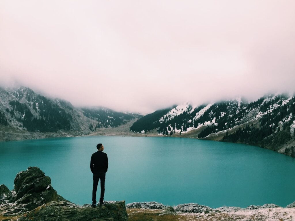 Un homme observe un paysage montagneux brumeux dans la contemplation de l'instant.