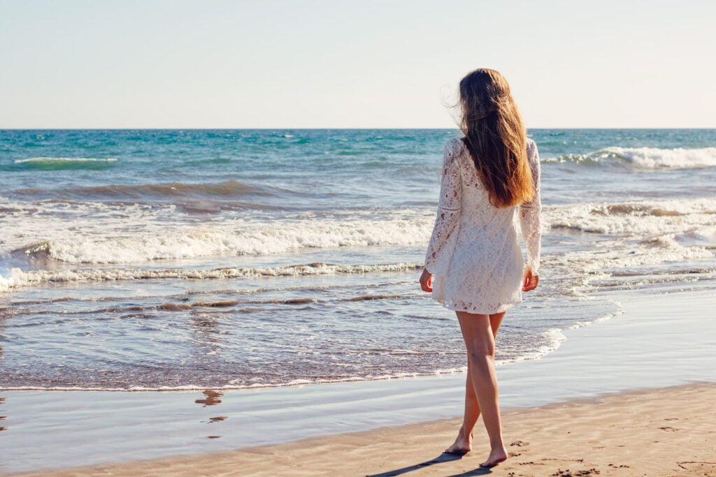 Une femme en marche contemplative devant la mer.