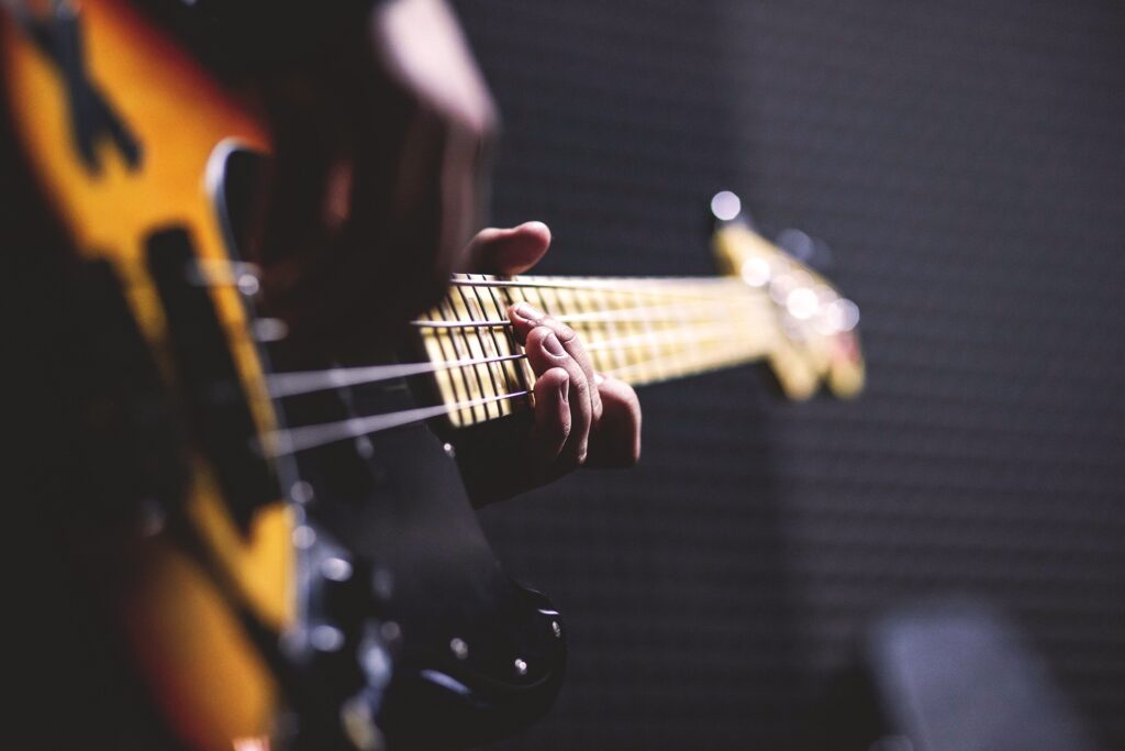 Un humain qui joue de la guitare ou en train de l'accorder, seul souverain de son instrument.